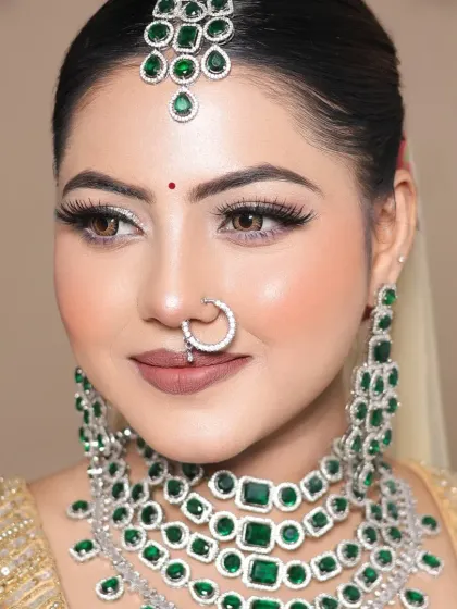 This student's work features a glamorous golden lehenga with emerald jewelry. The makeup is kept soft and neutral to let the outfit shine.