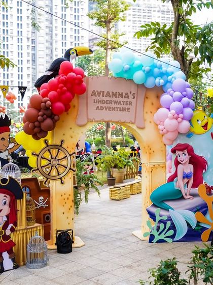 The entrance to an underwater adventure, this archway perfectly blends the pirate and mermaid themes with characters, balloons, and a custom sign.