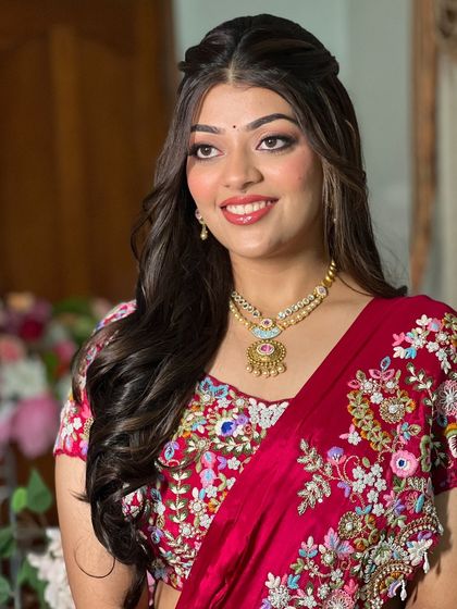 A portrait of a client with a classic half-updo and soft waves.