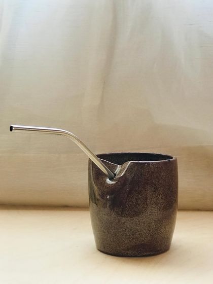 A "Sip Buddy" in a darker, speckled glaze. The earthy tones and practical design make it a perfect everyday cup.