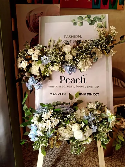 Branding can also be elegant and subtle. For this 'Peach' pop-up event, I decorated a simple welcome easel with beautiful white and blue floral arrangements to create an inviting entrance for guests.