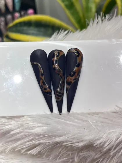 This design features a fierce snake with a leopard print skin, slithering over a matte black stiletto nail. A perfect example of combining different textures and patterns.
