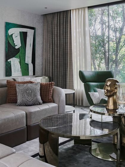 A detail shot of the Chennai family lounge, showing the interplay of textures and colors. The soft grey sofa, patterned cushions, and a bold piece of abstract art in green tones create a space that is both relaxing and visually engaging.