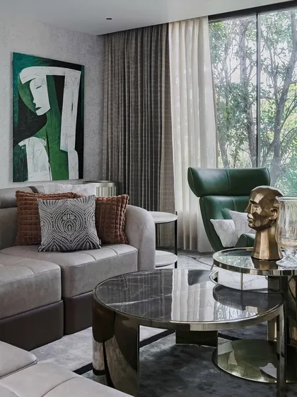 The interplay of art and furniture in the family lounge. A large abstract painting in green and white complements the leather chaise, while the round marble and metal coffee table adds a sculptural element.