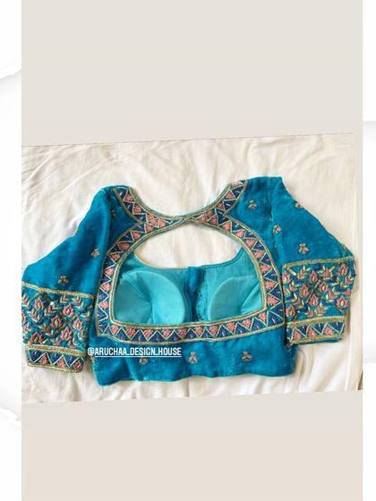 A beautiful turquoise velvet blouse with a modern back design. The sleeves and neckline are adorned with subtle floral embroidery and sequins for a touch of sparkle.