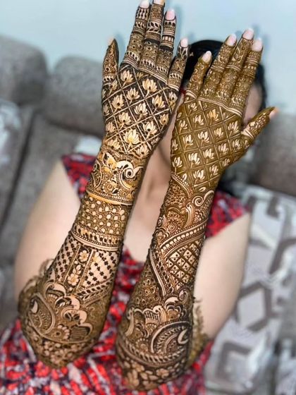 This full-coverage bridal mehendi features heavy jaal (net) patterns on the back of the hands, paired with intricate traditional motifs extending up the arms.
