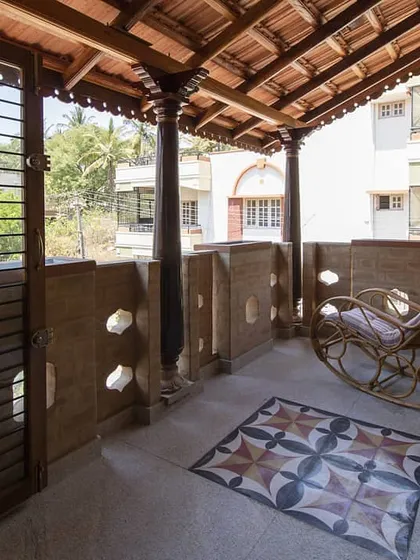 A peaceful balcony in the house for Shalini & Raghavendra, featuring rammed earth walls, traditional pillars, and a Mangalore tile roof.