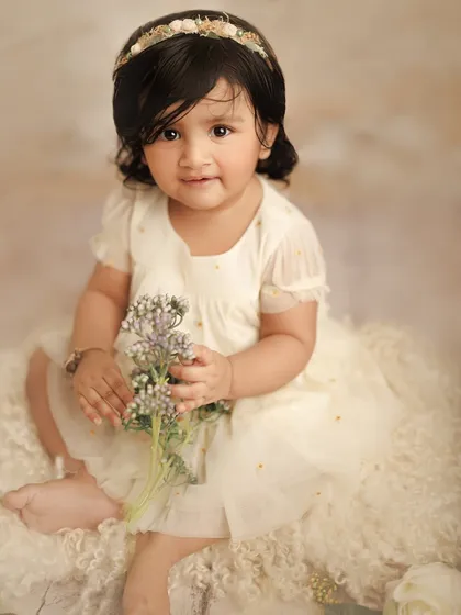 This sweet little girl, with a floral headband and a bouquet of tiny flowers, looks like a little angel. This is a beautiful example of a simple and classic baby portrait session.