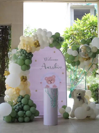 A gentle and modern "Welcome Aarshiv" party, using a soft green and white color palette with teddy bear accents.