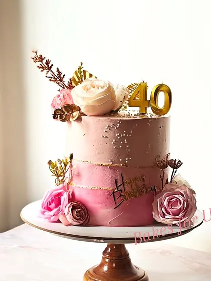 A lovely two-tier cake for a 40th birthday, decorated in shades of pink with fresh flowers and gold accents. The ombre effect adds a modern touch to this elegant design.