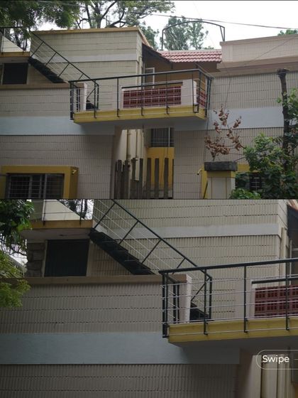 The exterior of the V S Sreedhara twin house, showing the projecting balconies and external staircase that give each home its own identity.
