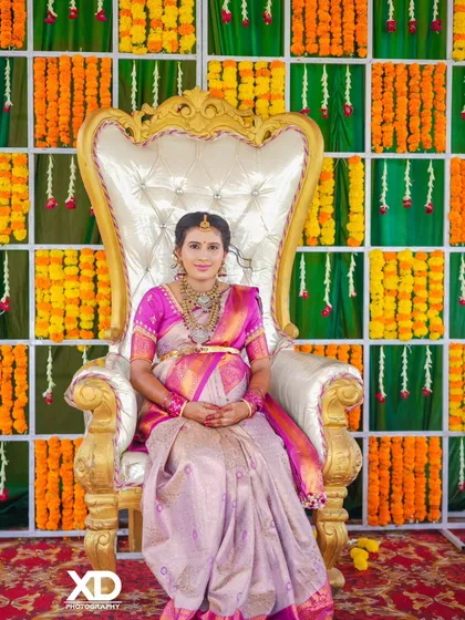 A full-length portrait of the mother-to-be seated on the ceremonial throne, looking graceful and elegant in her traditional saree.