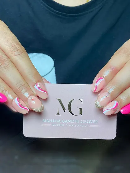 Fun and vibrant acrylic nail extensions. This playful design combines a hot pink polish with abstract white and gold glitter swirls on a neutral base, perfect for someone who loves a pop of color.