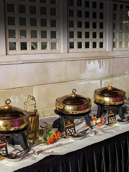 This is a classic example of my buffet setup, featuring a line of gleaming brass chafing dishes against a black-draped table. The arrangement is clean, elegant, and ready to serve a delicious feast for a formal event.