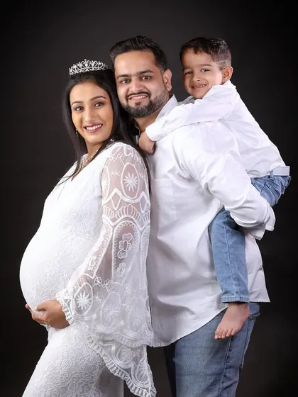 A classic family maternity portrait, with everyone smiling brightly for the camera.