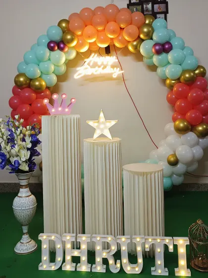A vibrant birthday decoration with a multi-colored balloon arch and a neon sign. This setup includes pedestals and light-up marquee letters, perfect for a cheerful celebration.