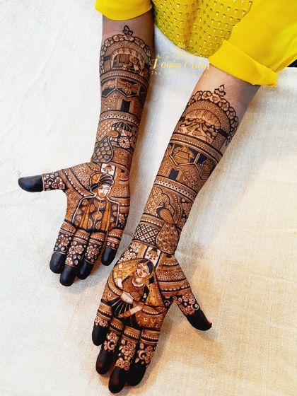 A beautiful bridal design featuring bride and groom portraits on the palms, with traditional elements like peacocks and elephants on the forearms.