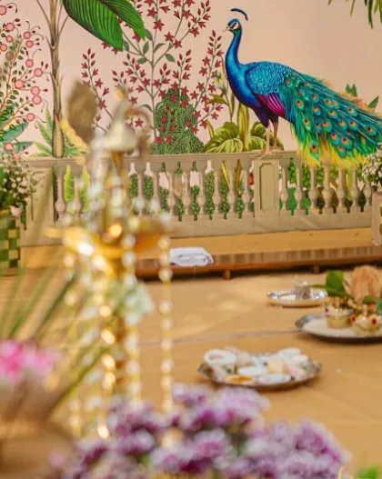 A slightly blurred foreground of a brass lamp focuses the view on the beautiful peacock backdrop. This composition highlights the layers and depth we create in our stage designs.
