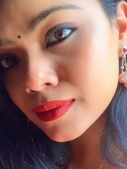 A close-up selfie showing a simple, elegant look with a red bindi and delicate earrings.