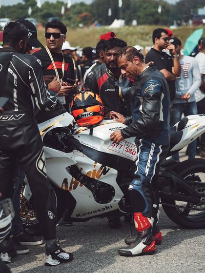 Racers discussing strategy by a Kawasaki superbike. The camaraderie and shared passion are what make the Vroom community so special.