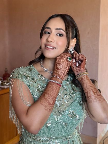 A candid moment of the bride putting on her earrings. This shot provides a great view of her intricate henna and the fresh, dewy finish of her makeup.