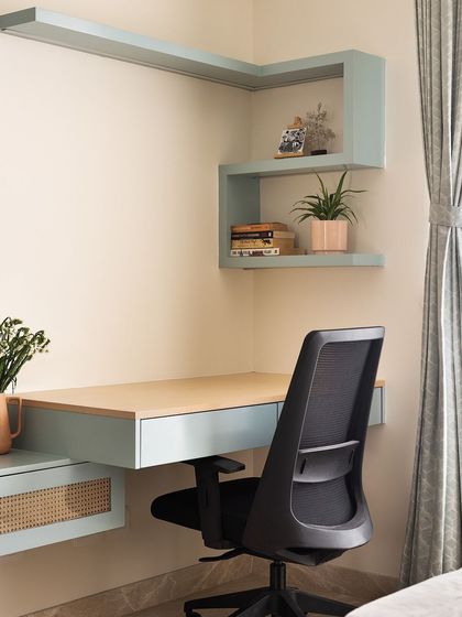 This study nook combines a soft, pastel blue with the warmth of a light wood desktop. The L-shaped corner shelving provides ample space for books and decor, creating a calm and productive workspace.