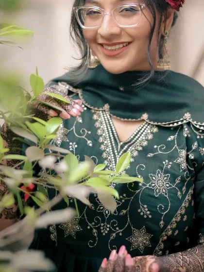 A beautiful portrait of a bride during her Mehendi ceremony. The natural greenery complements her embroidered green outfit, creating a fresh and modern traditional look.
