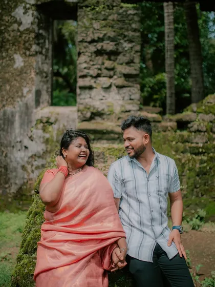 A joyful, laughing moment between a couple during their pre-wedding shoot in a park with ruins.