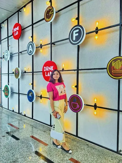 A fun, casual outfit with a bright pink graphic tee and pastel yellow pants, posing against a cool, graphic wall.