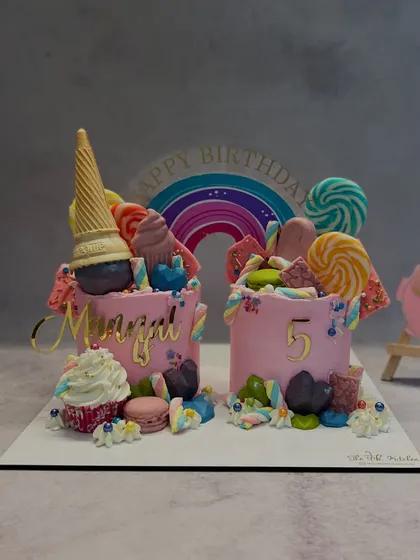 A candy lover's fantasy, this twin cake set is overflowing with treats like an upside-down ice cream cone, lollipops, macarons, and colorful candies. It's a vibrant and playful design for a fun-filled birthday party.