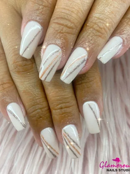 Clean, crisp, and incredibly chic. These coffin-shaped nails are painted in a solid off-white, with accent nails featuring fine, sparkling lines in silver and rose gold for a touch of modern, minimal glamour.