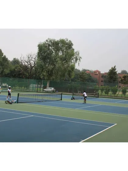 An overview of the tennis facility at Modern School, with several courts in use. The green surroundings and well-kept grounds provide a pleasant atmosphere for competitive play.