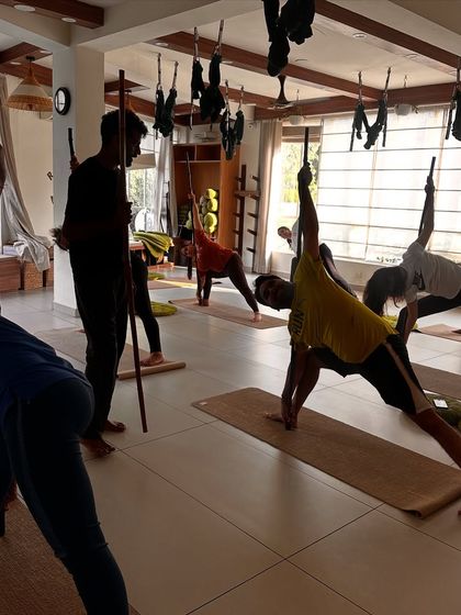 An instructor guides students through a triangle pose variation using sticks for alignment and support. This ensures a safe and effective stretch for the entire body.