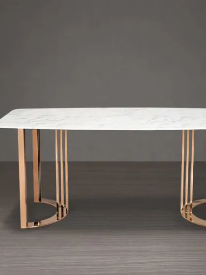 This modern dining table features a white marble top and a striking rose gold base with a cage-like design. It's available by order in the Mumbai, Thane, and Navi Mumbai regions.