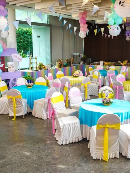 The dining area for the Hello Kitty party, featuring bright, cheerful tablecloths, chair covers, and themed centerpieces.