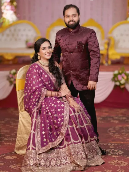 Another elegant portrait of the engaged couple. The bride is seated while her partner stands beside her, creating a timeless and well-composed photograph.