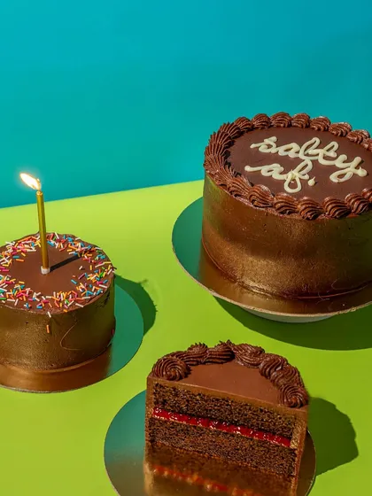 A trio of my celebration cakes, each with its own personality. You can see a classic birthday cake with sprinkles, a sassy chocolate cake, and a slice of our Raspberry Crunch Fudge.