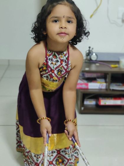 A portrait of the little girl in her traditional Garba choli, holding her dandiya sticks and ready to dance.