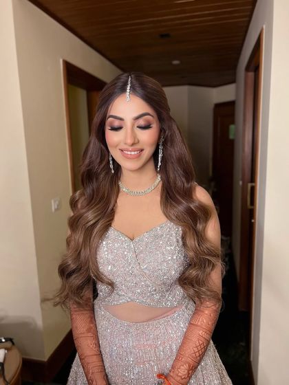 The bride smiling, her soft waves and simple maang tikka creating a look of pure enchantment.