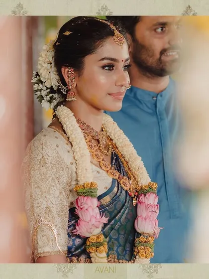 A bride during her wedding ceremony, wearing a blue Kanchipuram saree. Her custom off-white blouse is fully embroidered, creating a beautiful contrast.