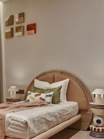 This kids' bedroom in a show apartment features custom-made bedside tables with a unique geometric design. The color palette of beige, grey, and orange is playful yet sophisticated.