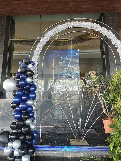 An elegant entrance for a music or star-themed event. The decor features a silver archway, star-shaped props, and a classic black, blue, and silver balloon garland for a sophisticated and celestial feel.