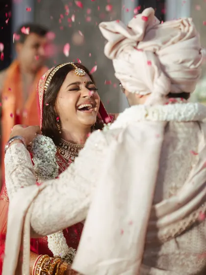 There's nothing like the pure joy of a bride on her wedding day. This candid shot captures that perfect moment of laughter, with her classic red lehenga and radiant makeup shining through.