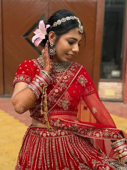 The addition of a fresh lily in her hair adds a touch of softness to this traditional red bridal look. It’s these small details that make each look unique.