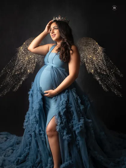 For a touch of fantasy, I can add elements like these glowing angel wings to a portrait. This shot in a blue gown creates a magical, ethereal vibe.
