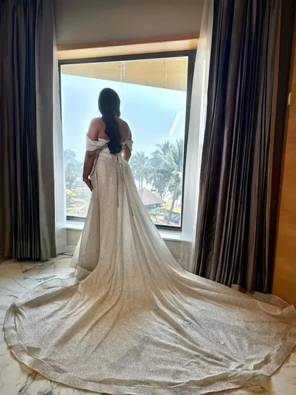 A breathtaking view from the back. The long, shimmering train of her wedding dress is a statement, complemented by a classic bridal hairstyle.