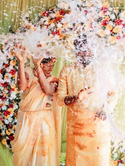 A dynamic shot of a couple being showered with water and flowers during their Haldi. We capture the peak of the action and excitement.