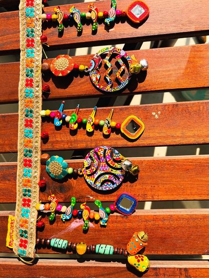 A close-up of the 'Rang-Tarang' toran, showing the hand-painted details on the wooden shapes and the tiny mirrors.