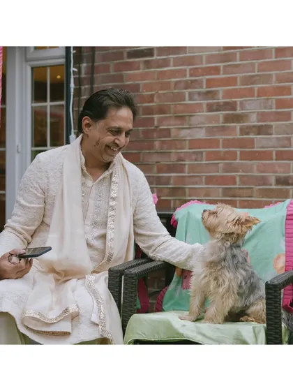 Shubham's dad shares a moment with the family dog, Sufi. This sweet, candid photo shows the warmth and love that fills a home on the morning of a wedding.
