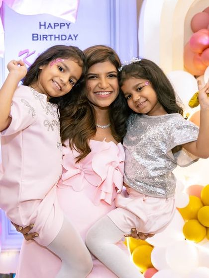 A lovely photo of a mother and her two daughters in front of a beautiful balloon backdrop.